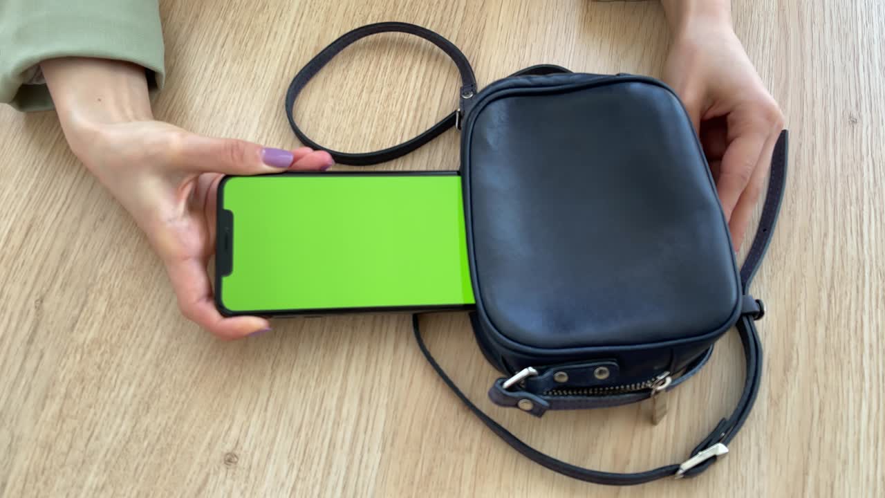 una mujer de 4k saca un teléfono móvil con pantalla verde de su bolsa.