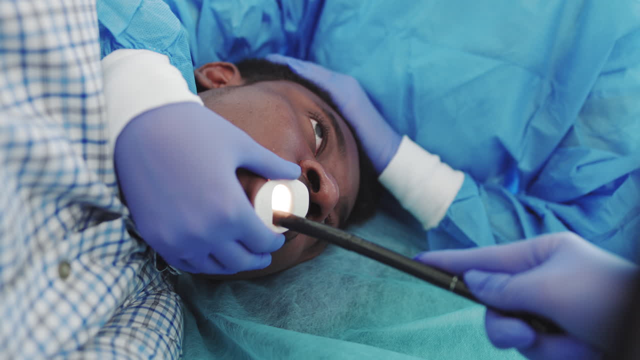 The doctor performs endoscopy through the mouth of a young africanamerican guy inserts a tubular