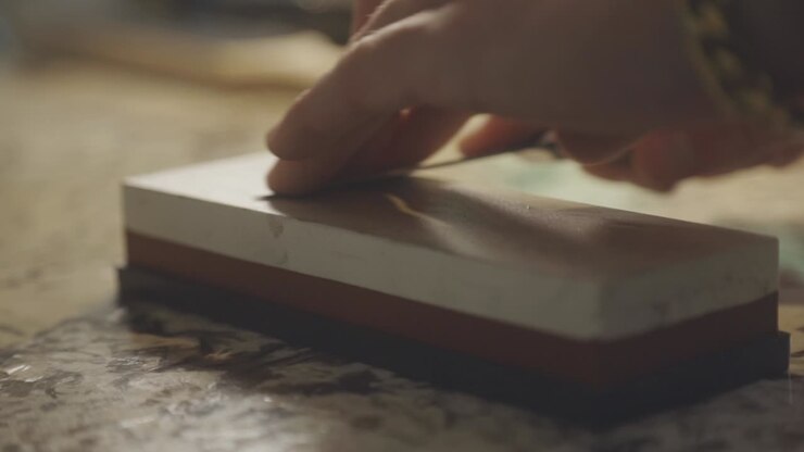 Close Up Of Sharpening Knife With Whetstone