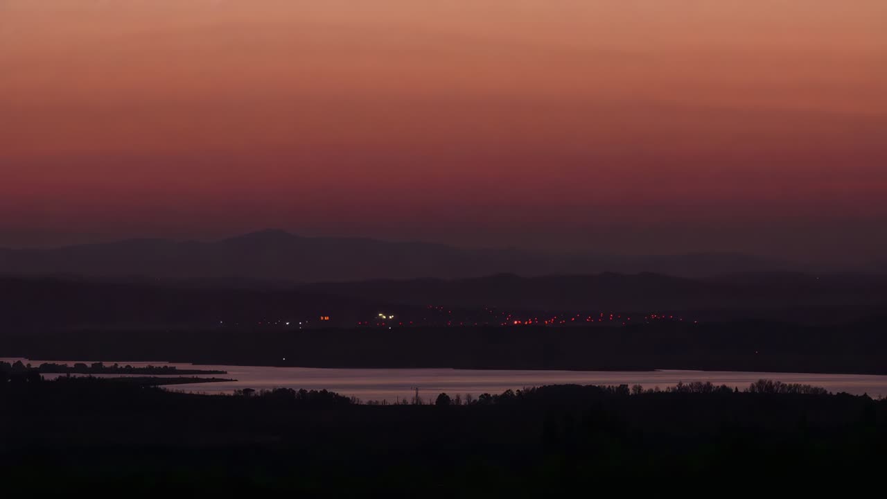 Watching distant red lights rising along shore as twilight deepening over lake, with white beacons
