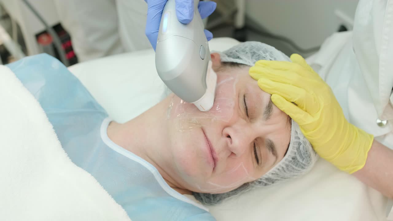 Professional face skin rejuvenation, lifting procedure. Cosmetologist uses modern ultrasound device. Hardware cosmetology
