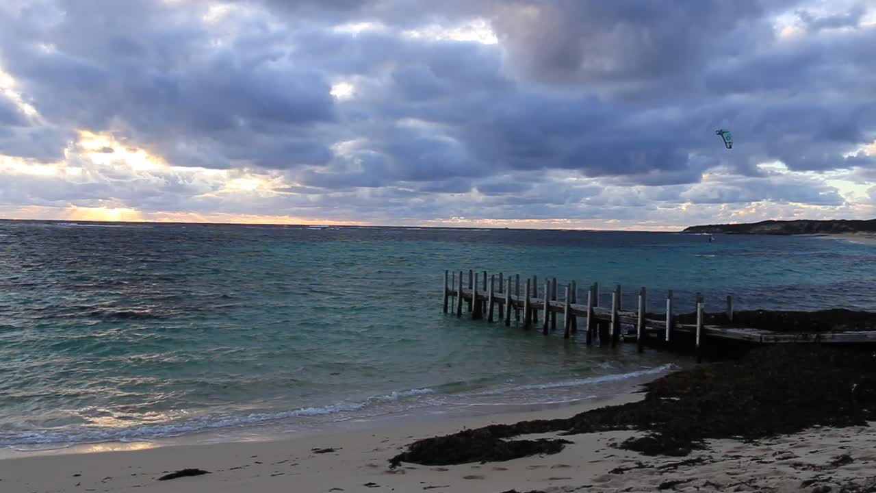 아래의 모래 해변 위에 분위기있는 파란색과 회색 하늘