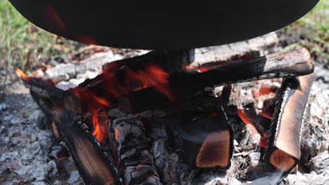 wood fire burns under large iron kettle cooking