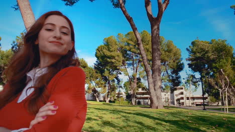 una mujer feliz, atractiva, joven, caucásica en el parque, mirando a la cámara - sonriente, orgullosa, con la barbilla en alto, lograda