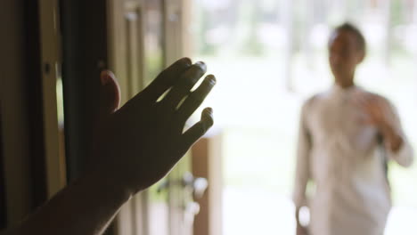 cerca de las manos del hombre saludando a su hijo que está parado en la entrada de la casa en un fondo borroso