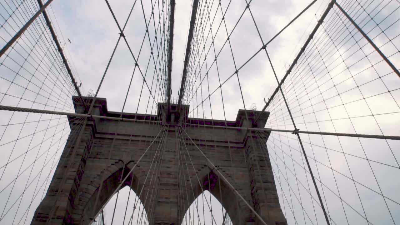 Splendida vista al rallentatore della griglia metallica sul Ponte di Brooklyn, New York, con un uccello che ci vola sopra. USA 1080p