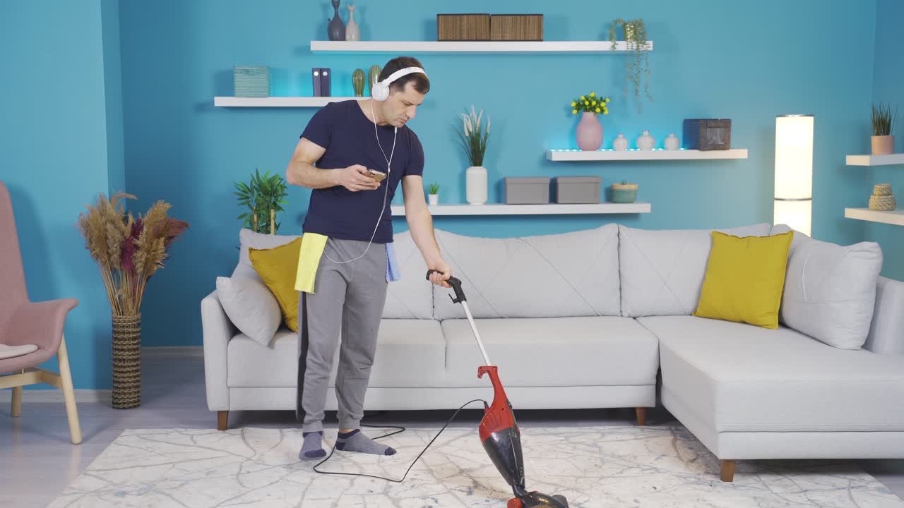 hombre torpe con el pie atrapado en el alambre mientras mira el teléfono mientras limpia. adicción al teléfono.