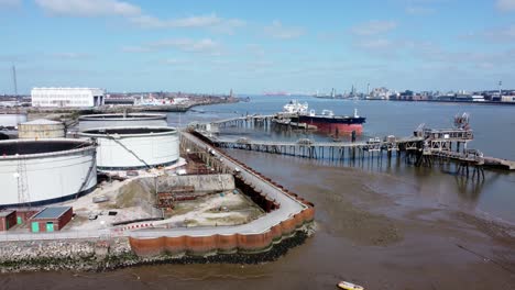 crude oil tanker ship loading at refinery harbour tanks aerial view dolly left