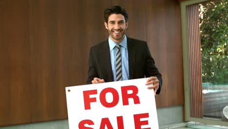 happy real estate agent with sold sign