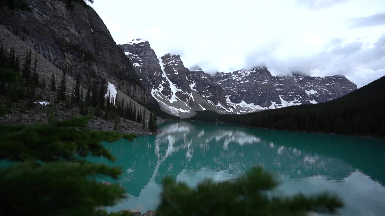 morrena de lago con montañas nevadas y nubes bajas en alberta, canadá