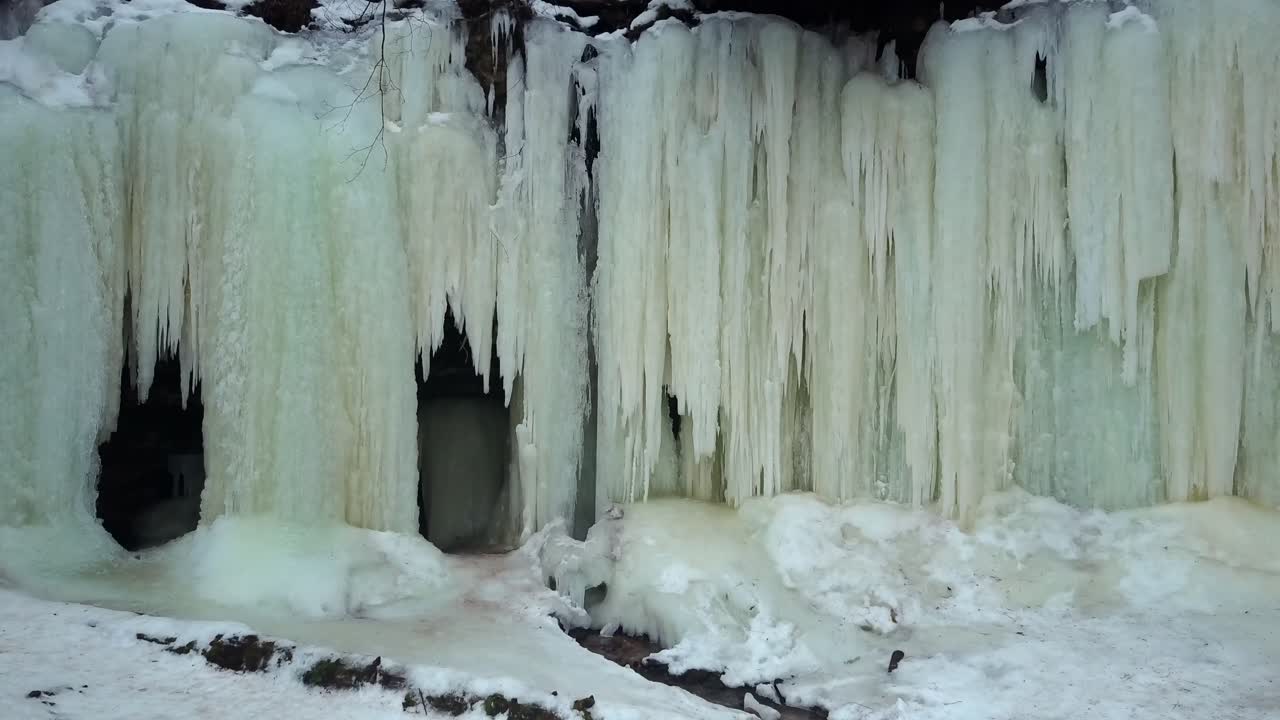 Frozen thick icicles at the entrance of Eben Ice Caves seen from outside, snow-covered ground in foreground. USA, zoom in