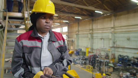 female worker walking in factory and putting on gloves