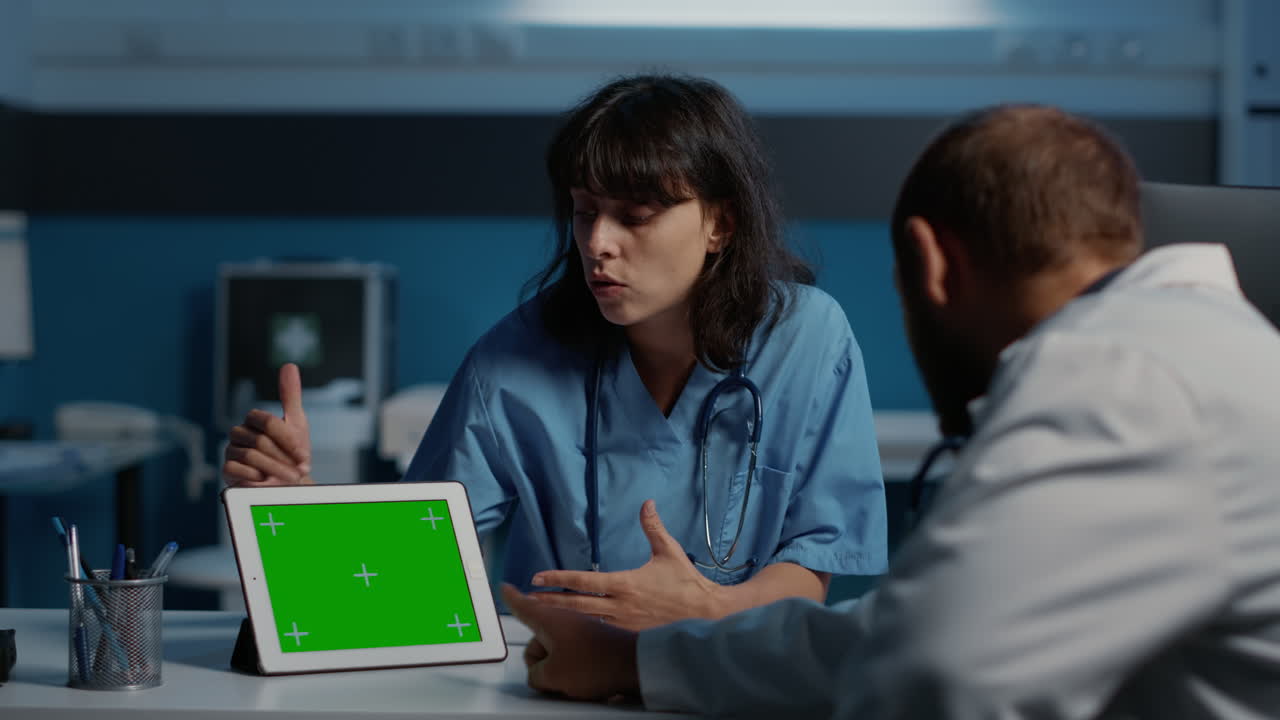 Doctors discussing medical information on a tablet with a green screen