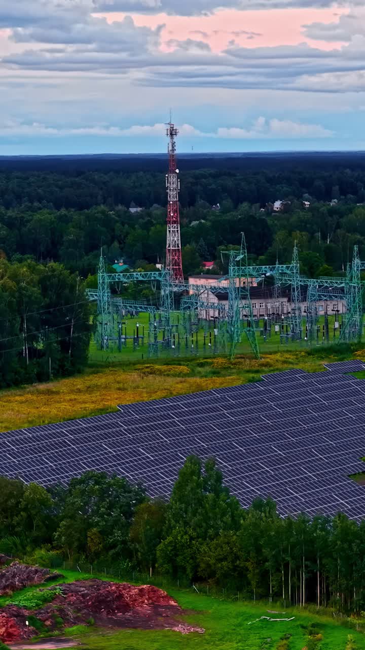 Aerial view of solar farm beside industrial area under a colorful sky