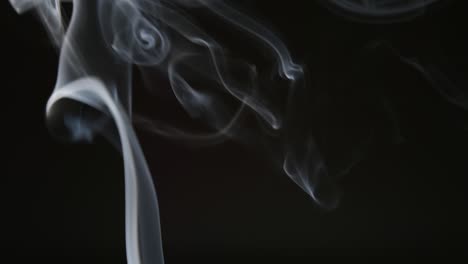 slow motion: curly line of smoke on a dark background