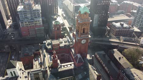 aerial drone flight over the rooftop of the refuge building on oxford road in manchester city centre with the camera panning down to slowly reveal a birdseye view of the clock tower and train station