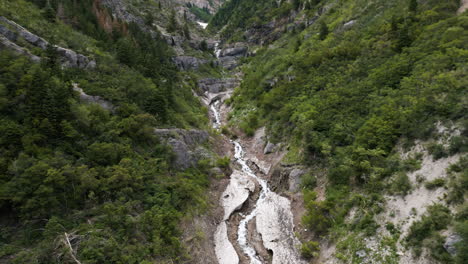 establishing aerial view rising from lush woodland valley slopes over glacial mountain stream in utah