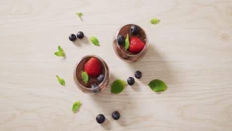 video of chocolate pudding with strawberries and bluberries on a wooden surface