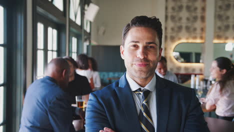 retrato de un hombre de negocios sonriente en una concurrida barra de cócteles de un restaurante con clientes en el fondo