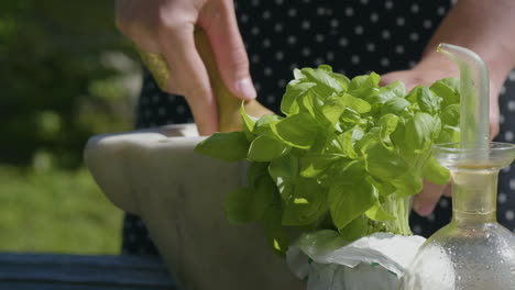 woman grinding basil leaves, making a pesto at a outdoor kitchen, in sunny italy