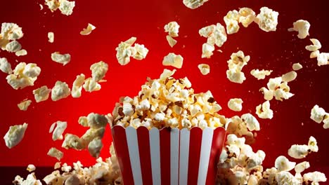 a red and white striped bucket of popcorn falling into the air