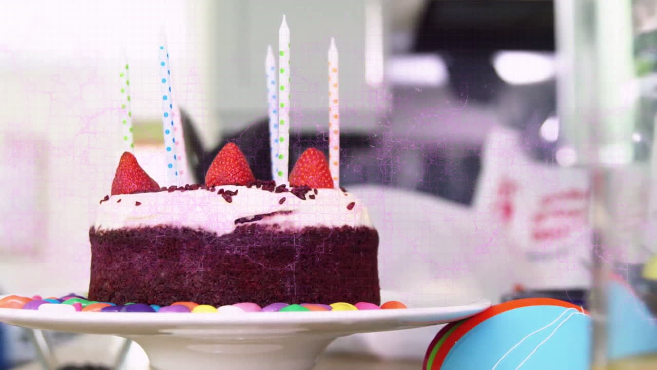 Strawberry birthday cake with candles on table, colorful decorations surrounding it