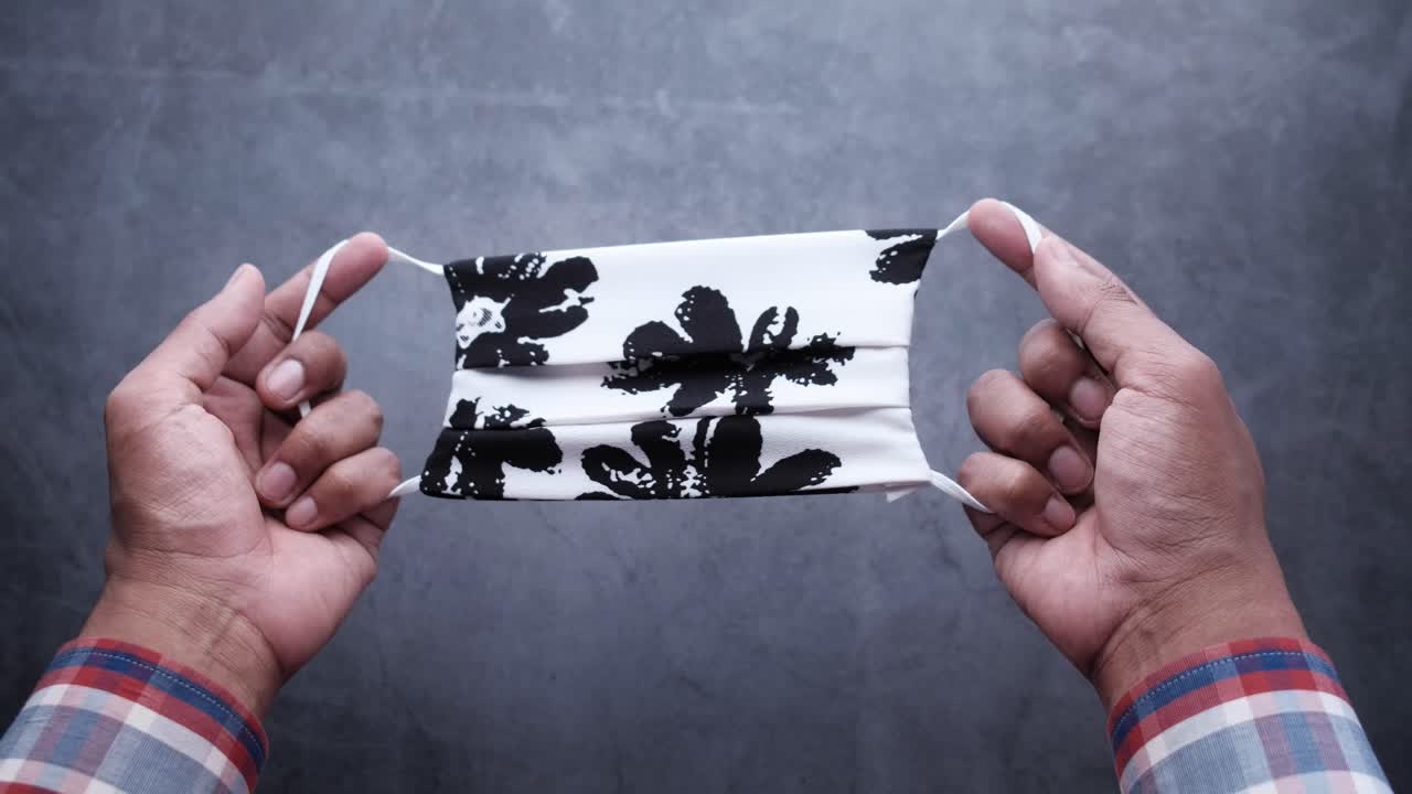 persona que sostiene una máscara facial de tela con patrones