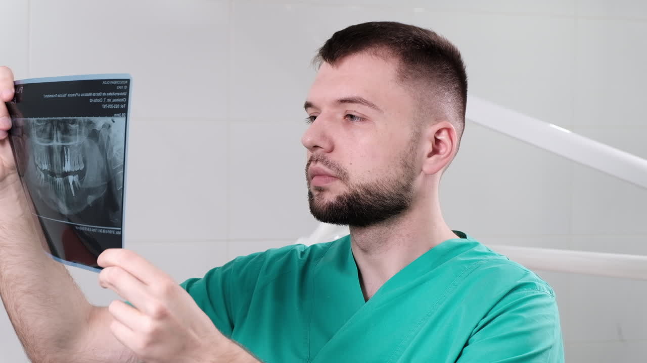 Doctor wearing green clothes in the dental office checking and explaining x-ray test