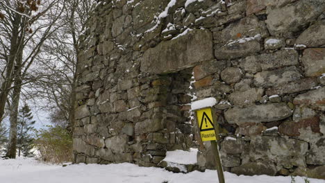 señal de peligro de caída de rocas en la ruina de la iglesia en el día de invierno