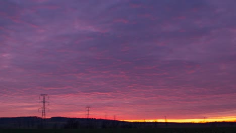 Zeitraffer-Von-Strommasten-Während-Eines-Bewölkten-Rotvioletten-Sonnenuntergangs
