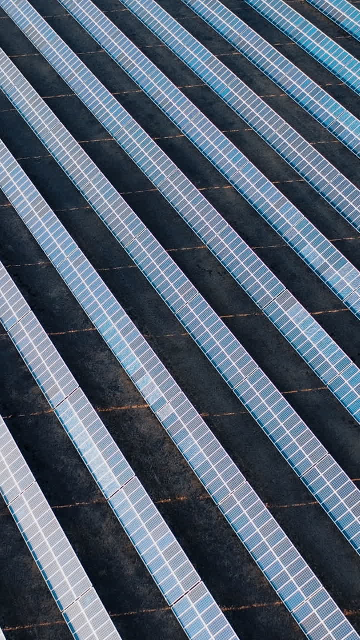 Drone view of solar power panels on black autumn fields at sunset. Aerial view. Vertical video