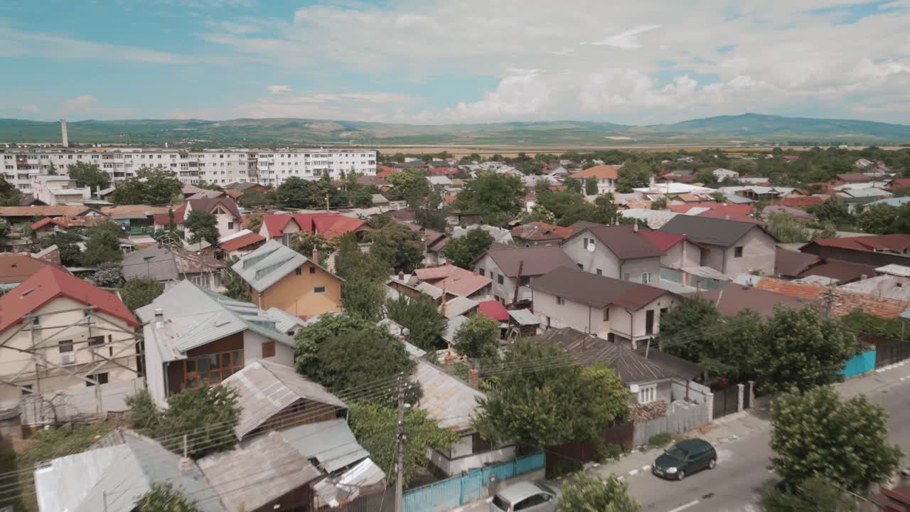 A small village with colorful rooftops surrounded by lush greenery on a sunny day, aerial view