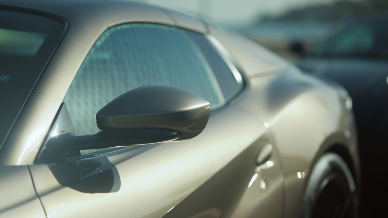 Sports car reflecting sunlight, highlighting its sleek golden finish and aerodynamic lines, symbolizing luxury and speed