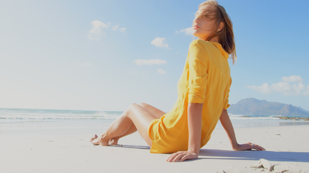 해변에서 휴식을 취하는 젊은 백인 여성의 측면 뷰 4k