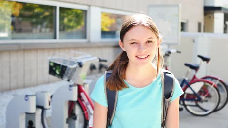 portrait of happy fifteen-year-old girl by city bikes