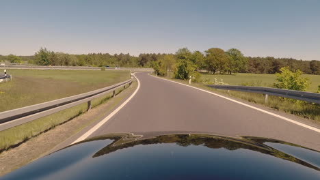 Schwarzes-Auto,-Das-In-Deutschland-Auf-Die-Autobahn-Fährt,-Blick-Vom-Dach-über-Die-Motorhaube-In-Zeitlupe