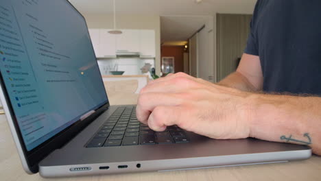 un hombre está escribiendo en su computadora portátil en casa