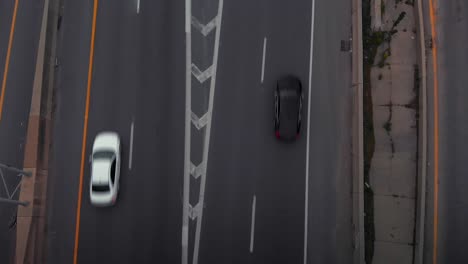 four-lane highway of vehicular traffic under two-lane bridge, directly above aerial approach