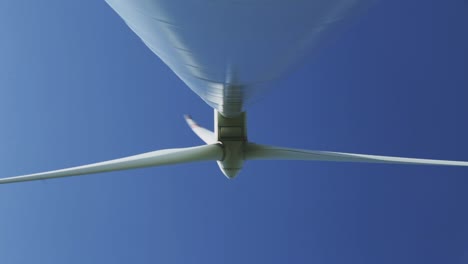 afternoon underneath perspective with wider standing footage from a wind turbine machine and its rotating blades