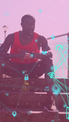 globos de iconos digitales contra el hombre afroamericano en forma usando un reloj inteligente sentado en las escaleras