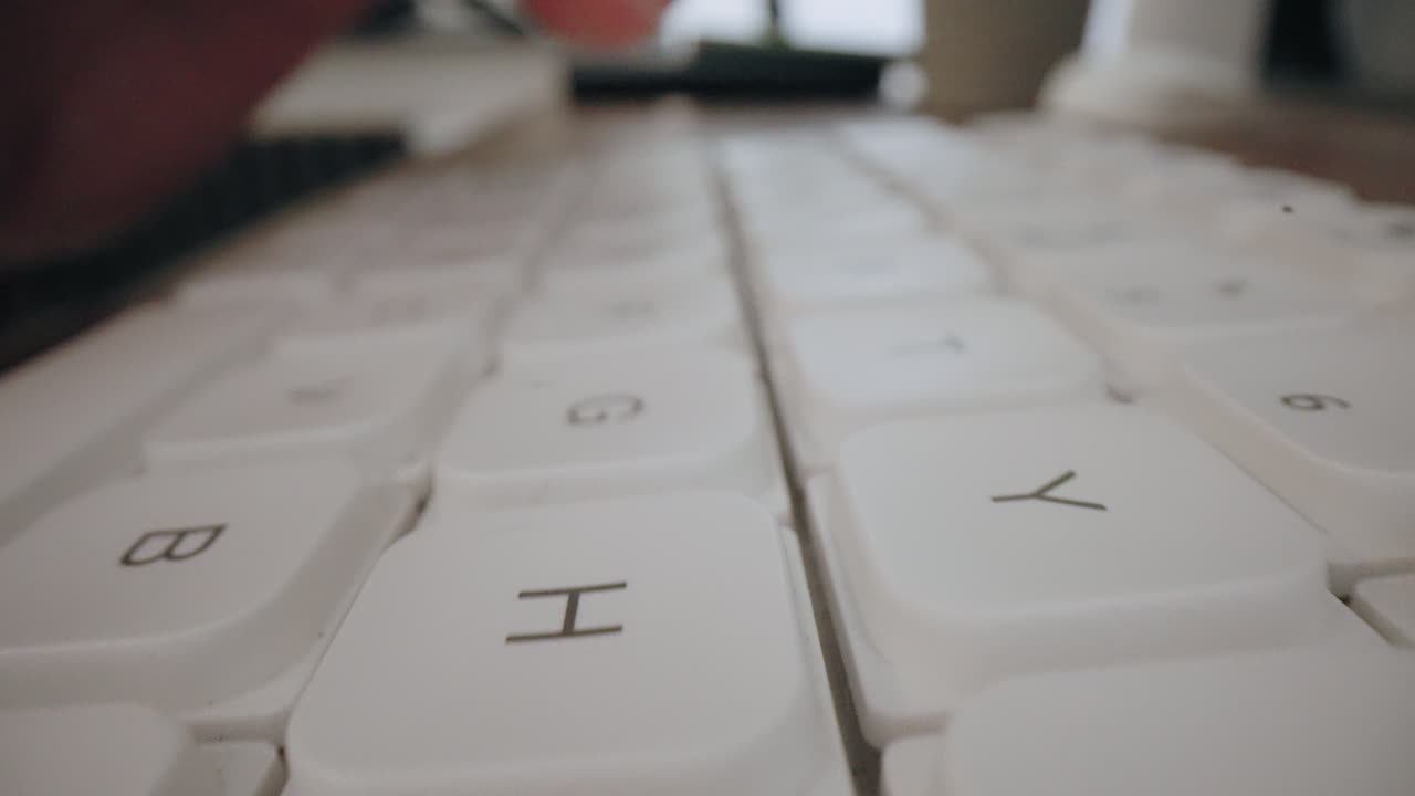 Close-up Moving Macro Shot: Man typing on computer keyboard - high-contrast backlit with shallow depth of field