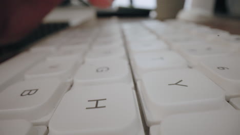 close-up moving macro shot: man typing on computer keyboard - high-contrast backlit with shallow depth of field