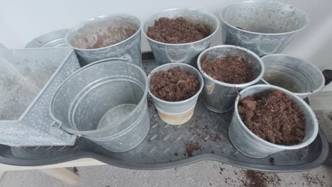 the pots are being loaded with soil, as the earth is carefully poured into them