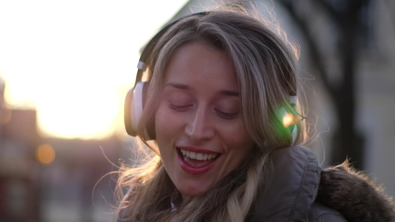 Sokakta şarkı söyleyip dans ederken kulaklıklarıyla müzik dinleyen kadın