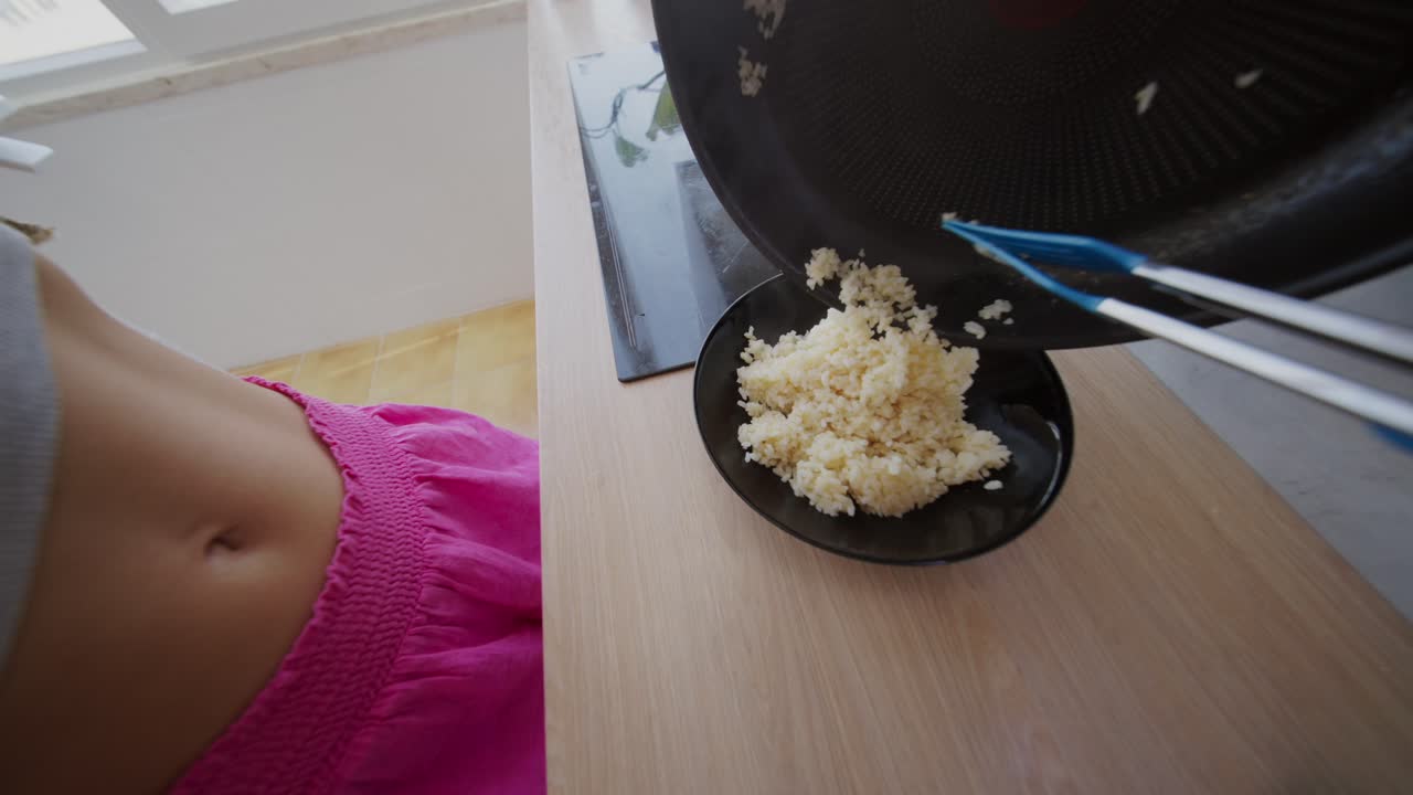 Transferring Cooked Rice from Pan to Plate in a Kitchen
