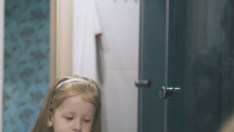 Mädchen-Mit-Blauen-Augen-Gurgelt-Vor-Spiegel-Im-Badezimmer