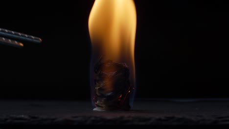 kindle fire using wood chips roll on black background. burning fire indoors in slow motion.