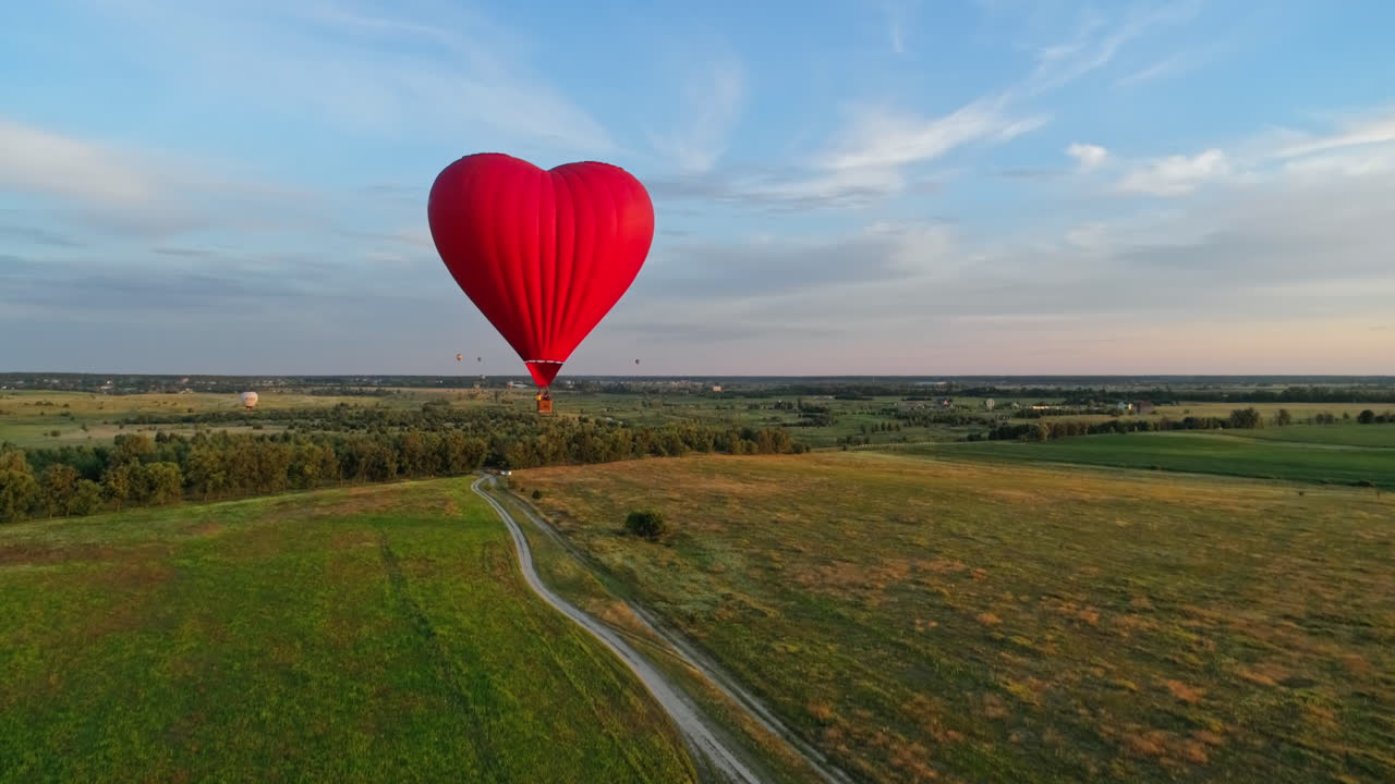 Red balloon in the sky. Balloon in the form of heart over fields
