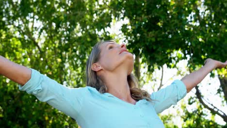 happy woman standing with hands raised in park