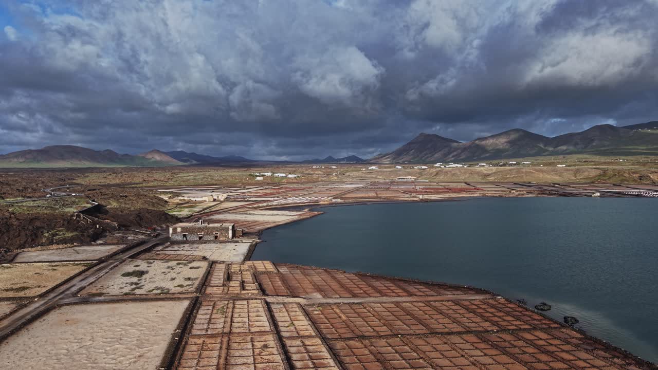 Campi di sale a Lanzarote, Spagna, con vegetazione e montagne.
